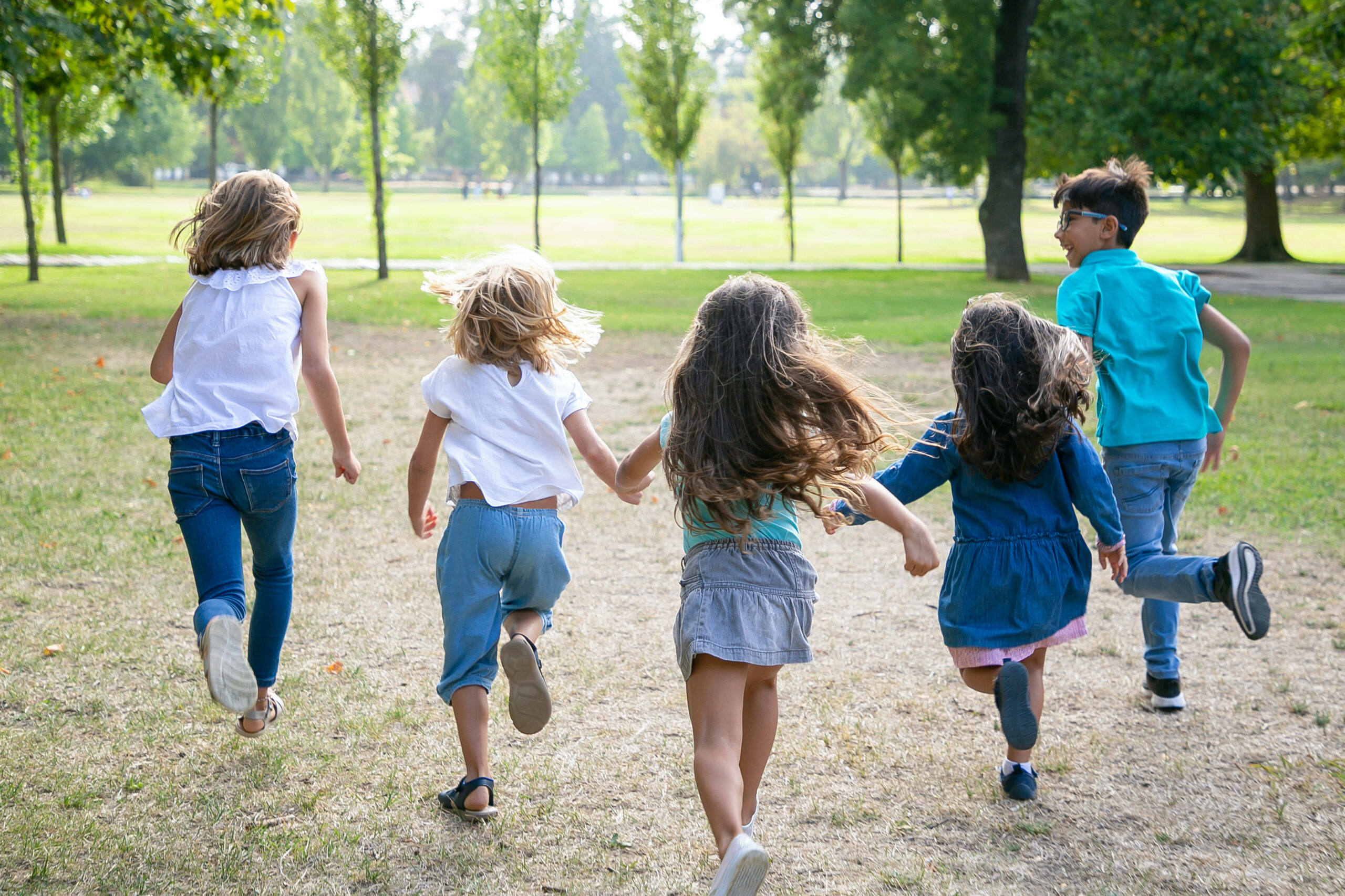 Grupo De Ninos Corriendo Juntos Sobre La Hierba Con Carrera En El Parque Vista Posterior De Cuerpo Entero Concepto De Actividad Al Aire Libre Para Ninos Scaled
